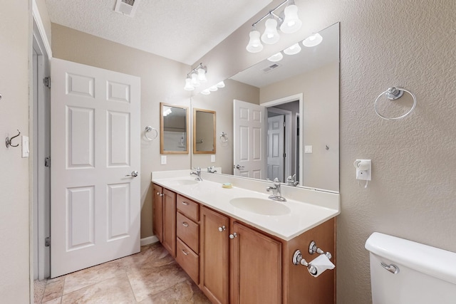 bathroom featuring vanity, a textured ceiling, and toilet