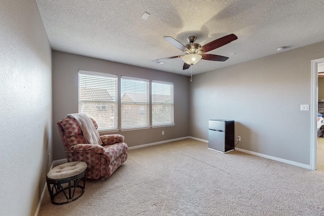 sitting room featuring ceiling fan, light colored carpet, and a textured ceiling