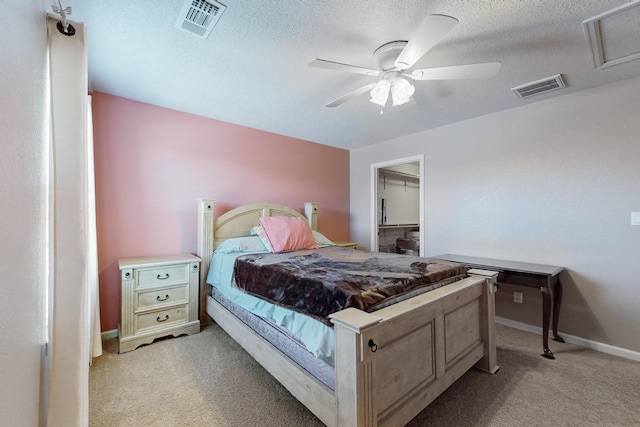 bedroom featuring ceiling fan, a textured ceiling, a walk in closet, light carpet, and a closet