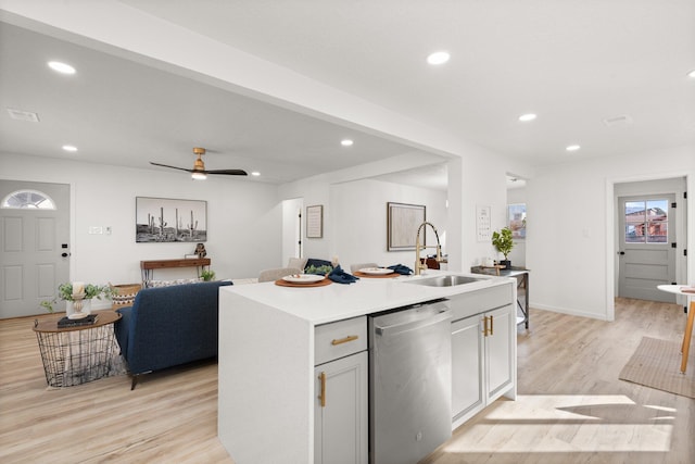 kitchen with ceiling fan, sink, stainless steel dishwasher, an island with sink, and light hardwood / wood-style floors