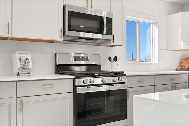 kitchen featuring decorative backsplash, white cabinetry, and appliances with stainless steel finishes