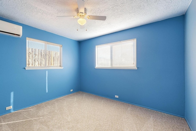 empty room with carpet flooring, a textured ceiling, a wall unit AC, and ceiling fan