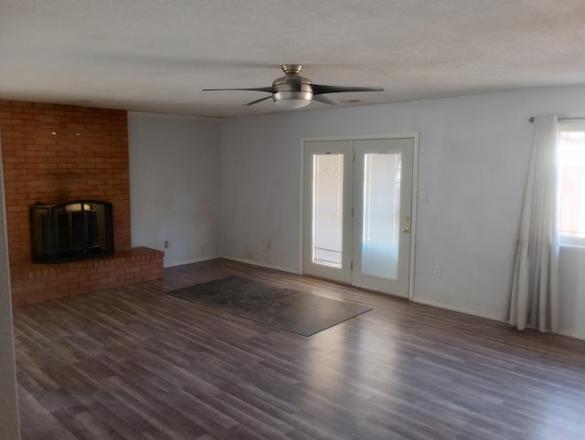 unfurnished living room featuring a brick fireplace, a textured ceiling, ceiling fan, and dark hardwood / wood-style flooring