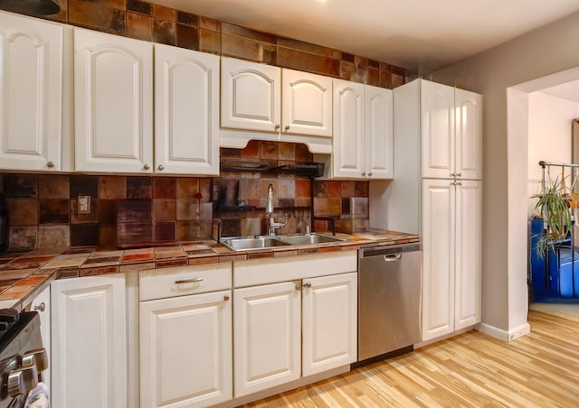 kitchen featuring appliances with stainless steel finishes, a sink, tile counters, and white cabinetry