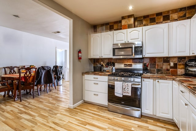 kitchen featuring white cabinetry, light wood-style flooring, appliances with stainless steel finishes, and decorative backsplash