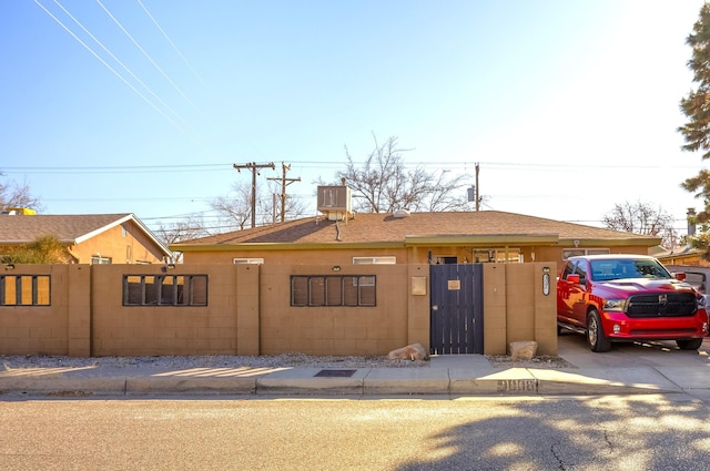 view of front facade with a fenced front yard, a gate, and a shingled roof