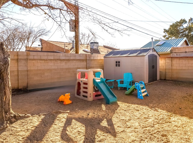 view of playground featuring a fenced backyard, an outdoor structure, and a storage shed