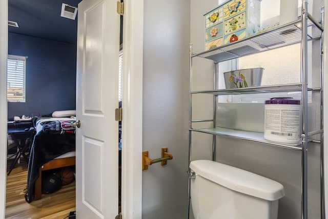 bathroom with toilet, visible vents, and wood finished floors