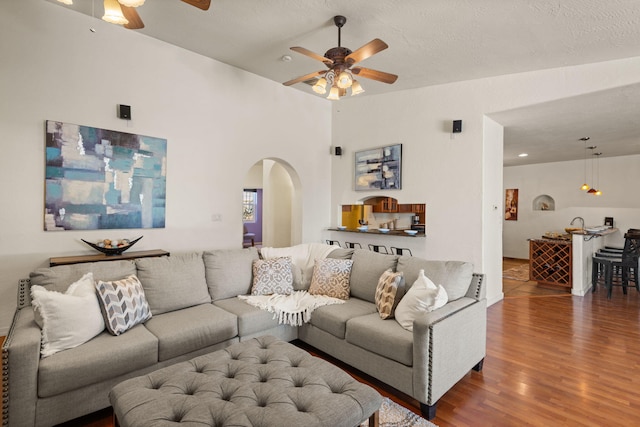 living room with a ceiling fan, arched walkways, and wood finished floors