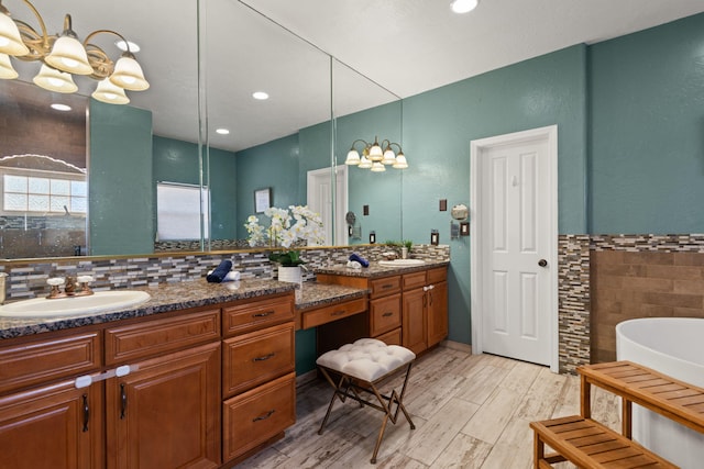 full bath featuring double vanity, a freestanding bath, tile walls, and a sink