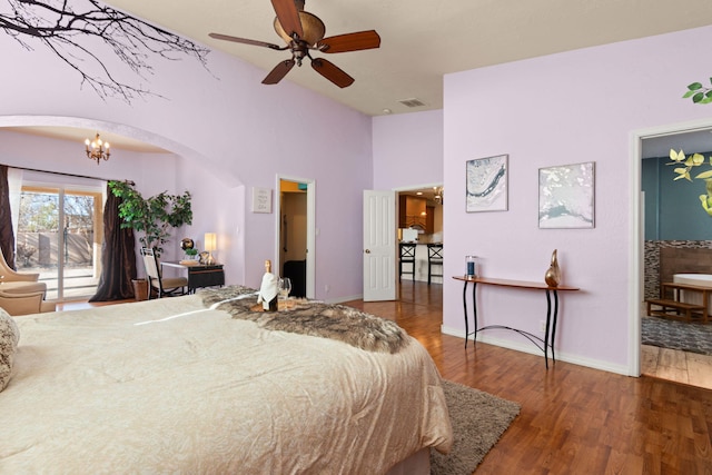 bedroom with arched walkways, visible vents, wood finished floors, access to outside, and baseboards