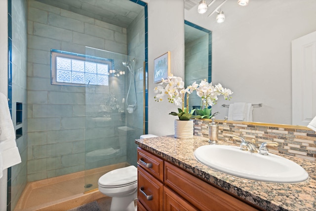 full bath with toilet, backsplash, tiled shower, and vanity