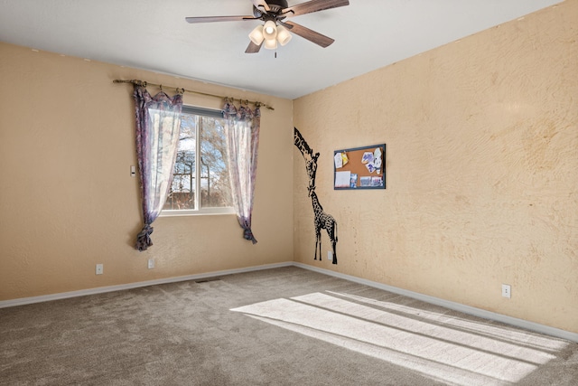 unfurnished room featuring carpet, visible vents, a textured wall, ceiling fan, and baseboards