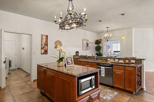 kitchen featuring brown cabinets, stainless steel appliances, a sink, a kitchen island, and dark stone counters