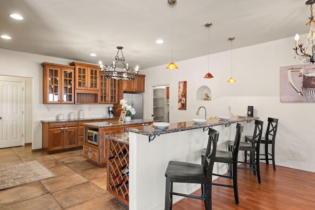 kitchen featuring a breakfast bar area, a kitchen island, appliances with stainless steel finishes, brown cabinets, and dark stone counters