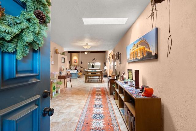 hall with a textured ceiling and a skylight