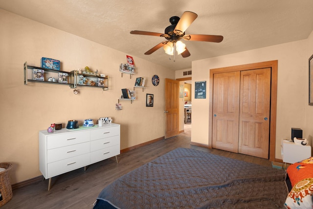 bedroom with dark hardwood / wood-style flooring, ceiling fan, a closet, and a textured ceiling