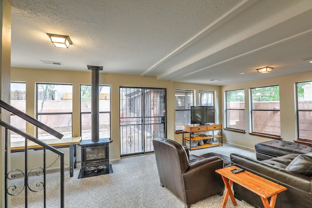 carpeted living room with a wood stove and a textured ceiling