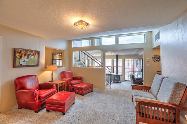 carpeted living room with a wood stove and a textured ceiling