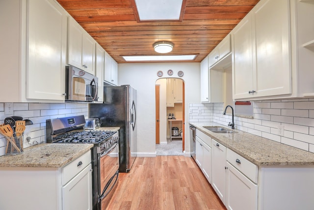 kitchen with stainless steel appliances, sink, white cabinets, and light stone counters