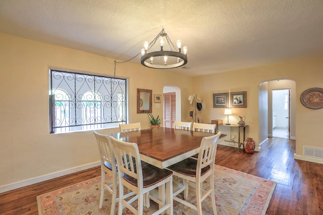 dining room featuring dark hardwood / wood-style floors, a textured ceiling, and a notable chandelier