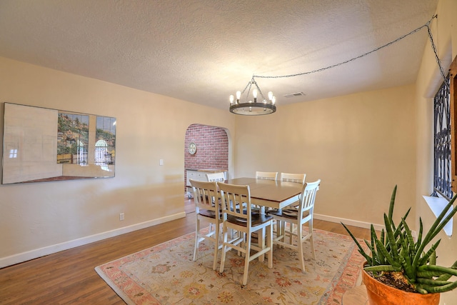 dining area featuring hardwood / wood-style floors, a notable chandelier, and a textured ceiling