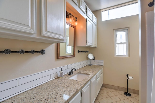 kitchen with sink, a wealth of natural light, white cabinets, and light stone counters