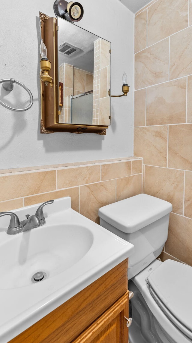 bathroom with vanity, toilet, and tile walls