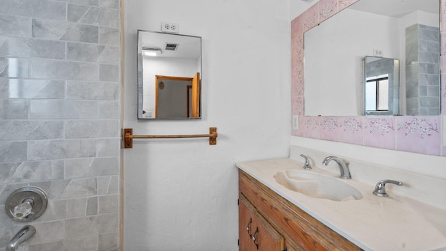 bathroom featuring vanity and tiled shower / bath