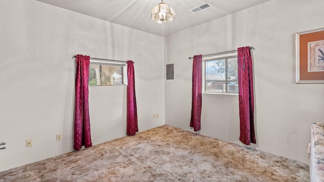 carpeted empty room with an inviting chandelier