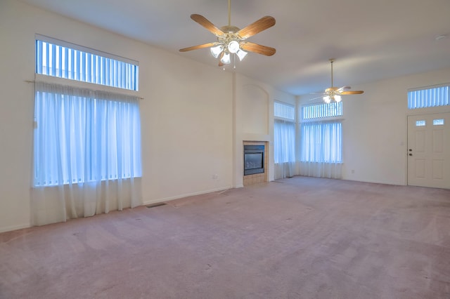 unfurnished living room featuring light carpet, a high ceiling, and ceiling fan