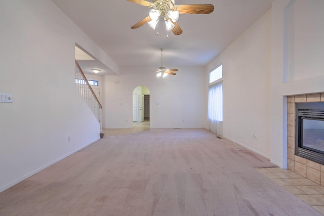 unfurnished living room with a fireplace, ceiling fan, and light carpet