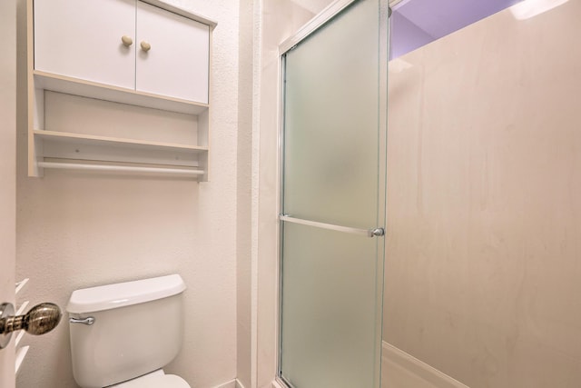 bathroom with a shower with door and toilet