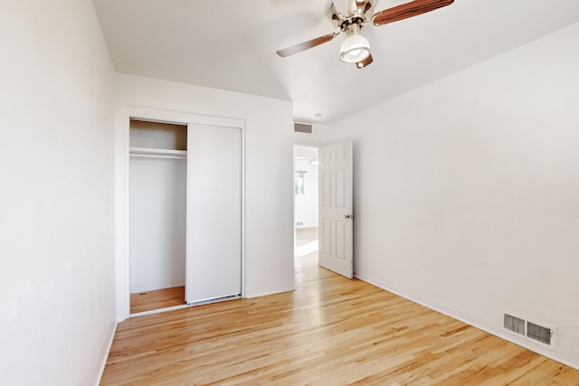 unfurnished bedroom with ceiling fan, light wood-type flooring, and a closet