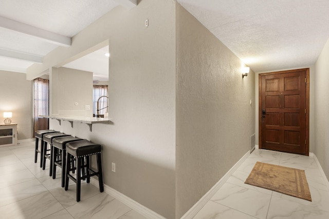 hallway featuring beamed ceiling and a textured ceiling