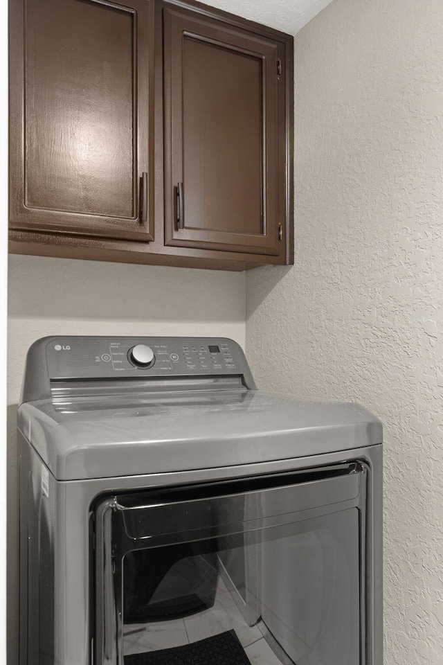 laundry area featuring tile patterned floors, cabinets, and washer / clothes dryer