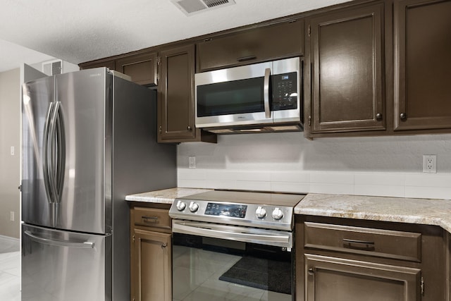 kitchen featuring dark brown cabinets, light tile patterned flooring, and stainless steel appliances