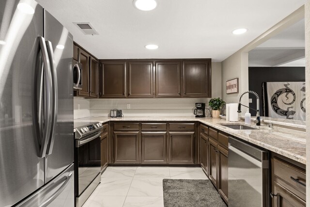 kitchen with sink, stainless steel appliances, light stone counters, kitchen peninsula, and dark brown cabinets