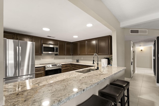 kitchen featuring sink, light stone countertops, light tile patterned flooring, kitchen peninsula, and stainless steel appliances