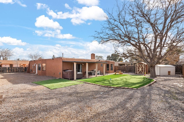 back of house with a patio area, a hot tub, and a storage unit