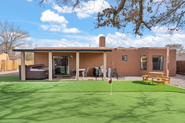 rear view of property featuring a patio and a hot tub