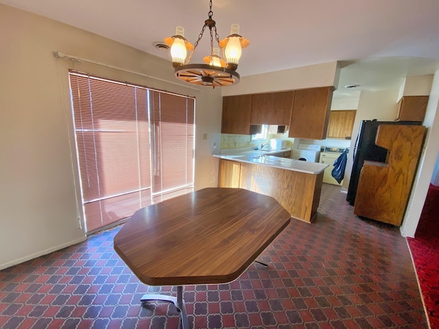 kitchen with pendant lighting, plenty of natural light, a notable chandelier, separate washer and dryer, and kitchen peninsula