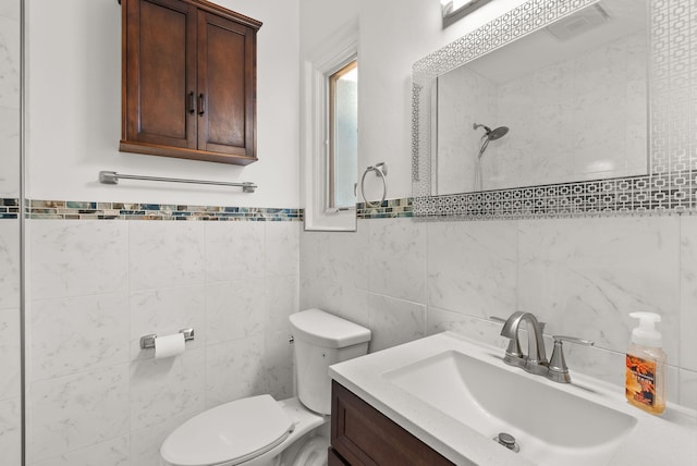 bathroom featuring walk in shower, vanity, toilet, and tile walls