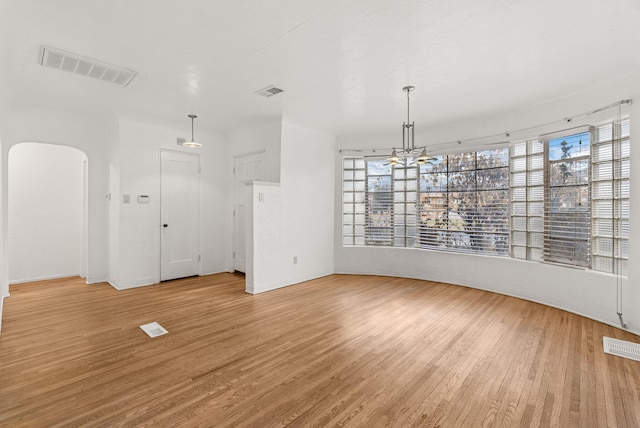 unfurnished dining area with a chandelier, light wood-type flooring, and plenty of natural light