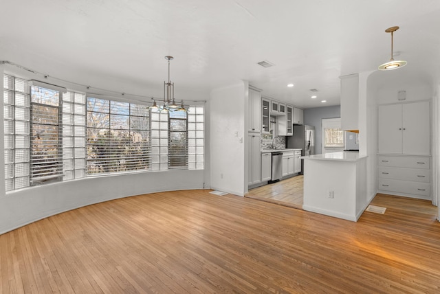 kitchen featuring kitchen peninsula, decorative light fixtures, backsplash, and stainless steel appliances