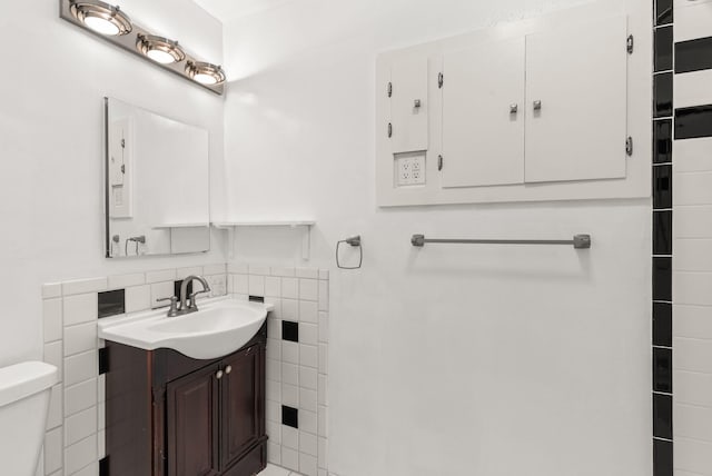 bathroom featuring vanity, tile walls, and toilet