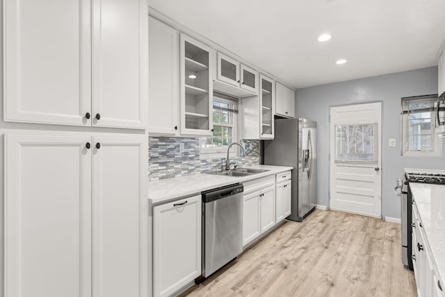 kitchen featuring white cabinets, sink, light stone countertops, tasteful backsplash, and stainless steel appliances