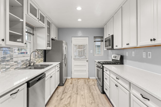 kitchen featuring light stone counters, stainless steel appliances, white cabinetry, and sink