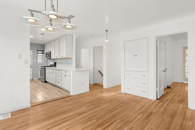 kitchen featuring white cabinetry, hanging light fixtures, light wood-type flooring, and appliances with stainless steel finishes