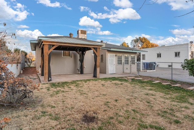 rear view of property with a gazebo, a patio area, and a lawn